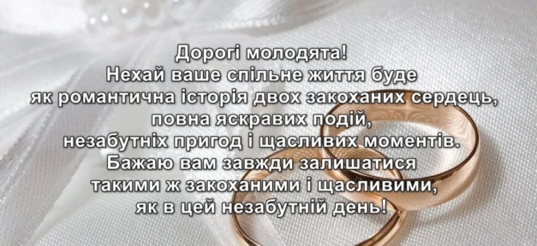 Золоті обручальні кільця на білому фоні з привітанням.