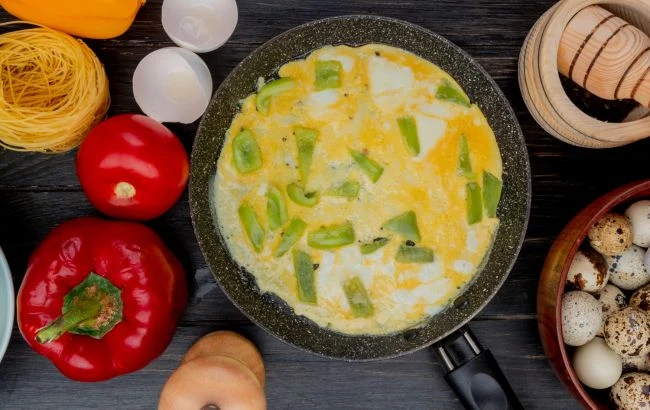 Готовий омлет з перець у сковорідці серед свіжих продуктів