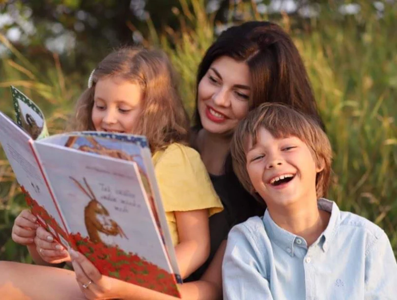 Мама читає книгу дітям на природі