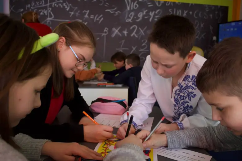 Діти спілкуються та працюють разом за партою в класі