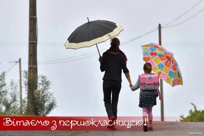 Жінка з дитиною йдуть до школи під парасольками