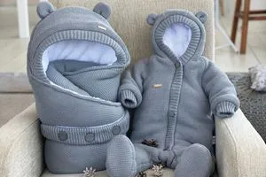 Два сірі м'які дитячі речі у формі ведмедиків на кріслі.